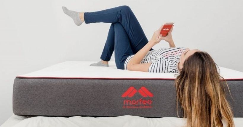 photo of woman laying on colchon morfeo mattress using her phone